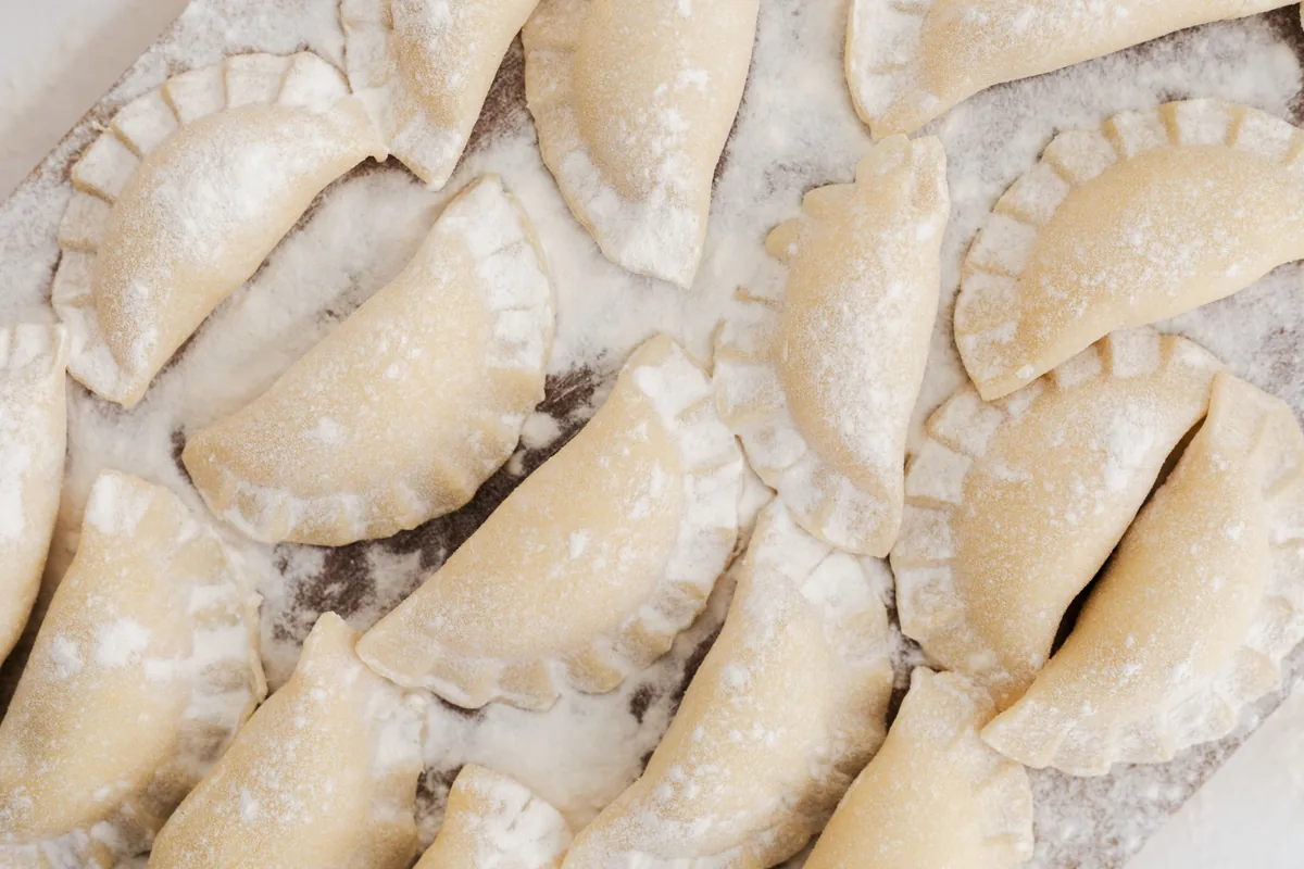 Surowe pierogi oprószone mąką, ułożone przed mrożeniem na Wigilię