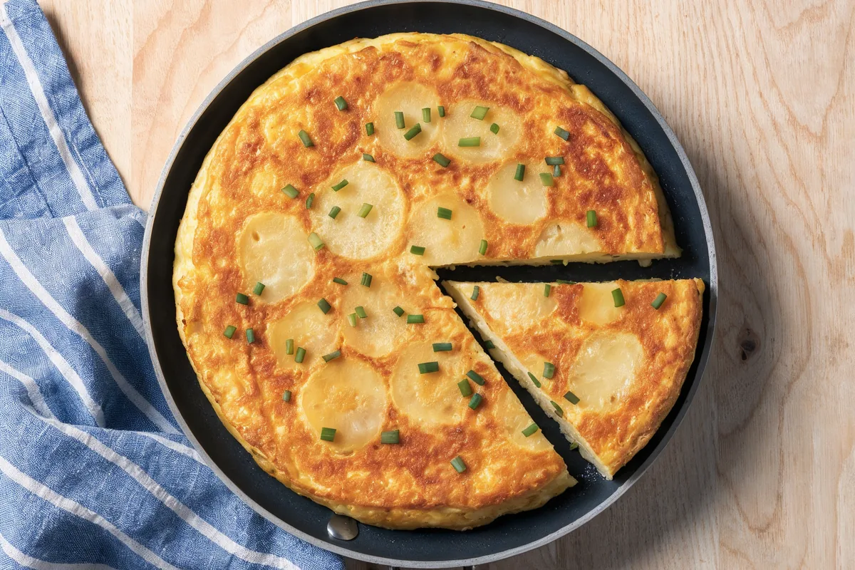 Frittata z ziemniakami z wczoraj na małej patelni, z jednym wykrojonym trójkątem