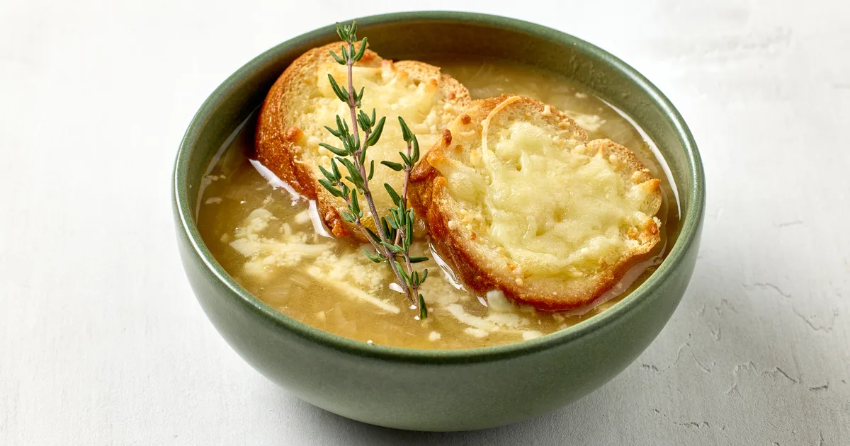 Francuska zupa cebulowa w żaroodpornej misce, na wierzchu grzanka z zapieczonym, zrumienionym serem