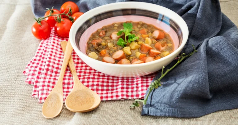 Zupa fasolowa w głębokiej misce: białe ziarna fasoli, kostki boczku, marchwi i ziemniaków, posypka z majeranku