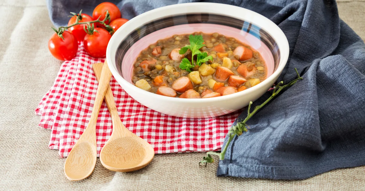 Zupa fasolowa w głębokiej misce: białe ziarna fasoli, kostki boczku, marchwi i ziemniaków, posypka z majeranku